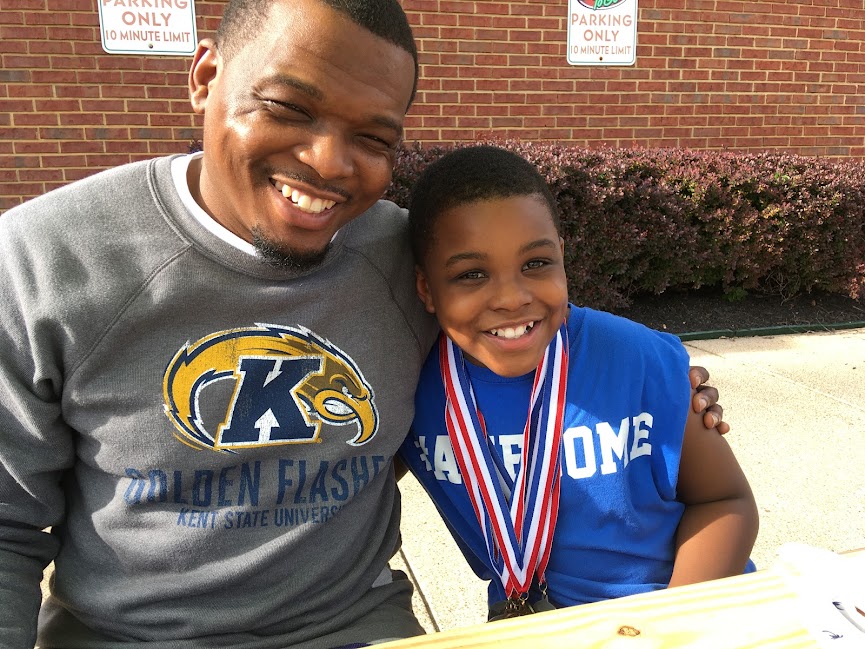 Jelp and his son smiling together, his son wearing gymnastics medals